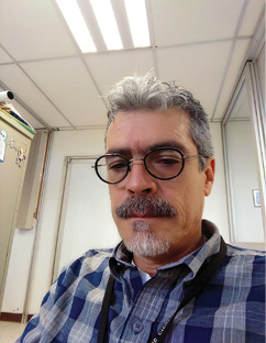 Un hombre con lentes y camisa de cuadros

Descripción generada automáticamente
